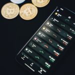 Coins scattered near smartphone with financial charts on screen